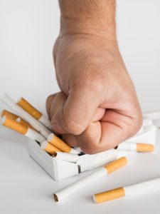 Puño aplasta caja de cigarros.
