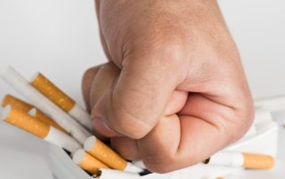 Puño aplasta caja de cigarros.
